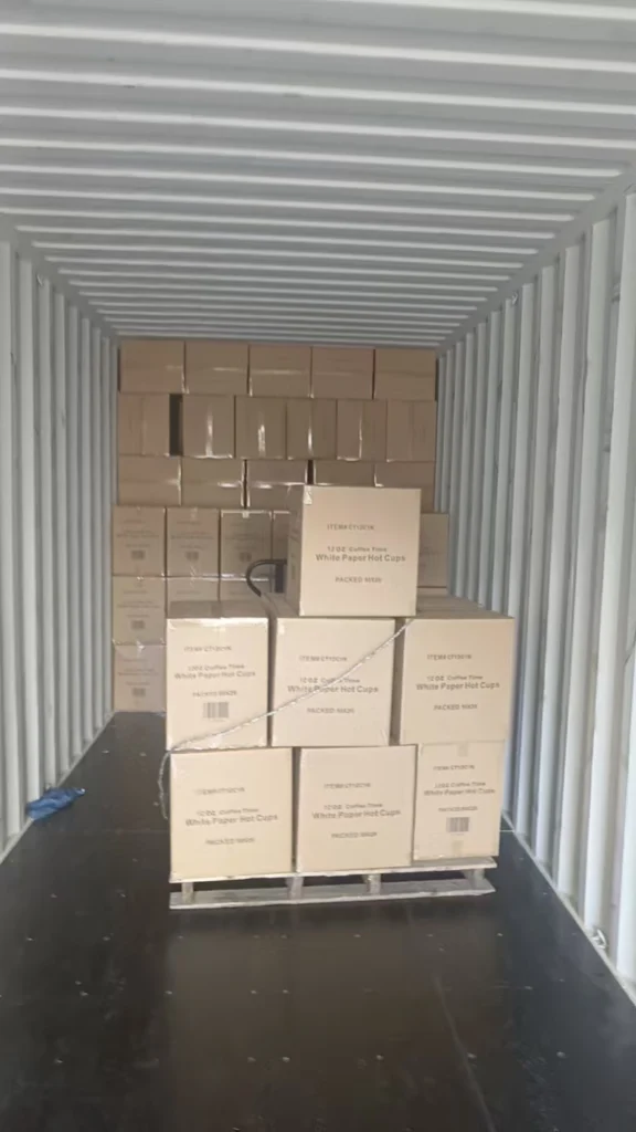 Workers loading cartons of disposable paper packaging into a shipping container